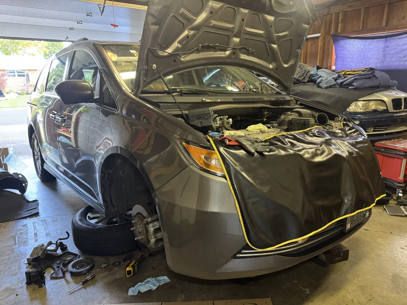 2015 Honda Odyssey with the hood open and front wheel removed during service.