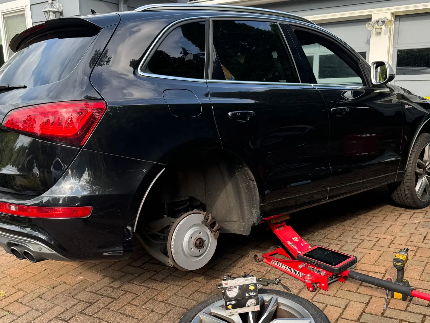 Black 2016 Audi SQ5 raised with a rear wheel removed during front and rear brake service.