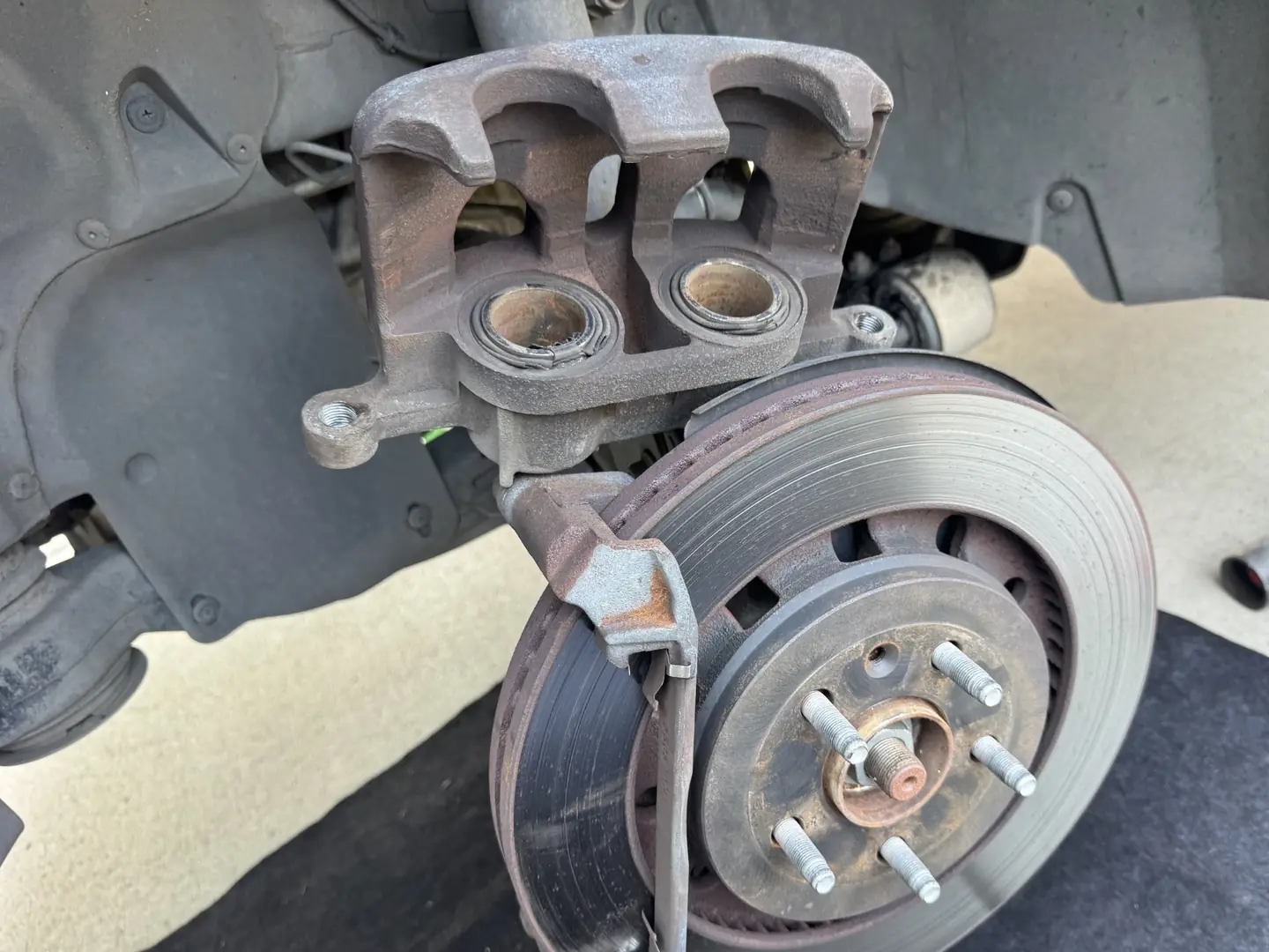 Front brake caliper with damaged piston seals and a heat-worn rotor on a 2017 Ford Explorer.