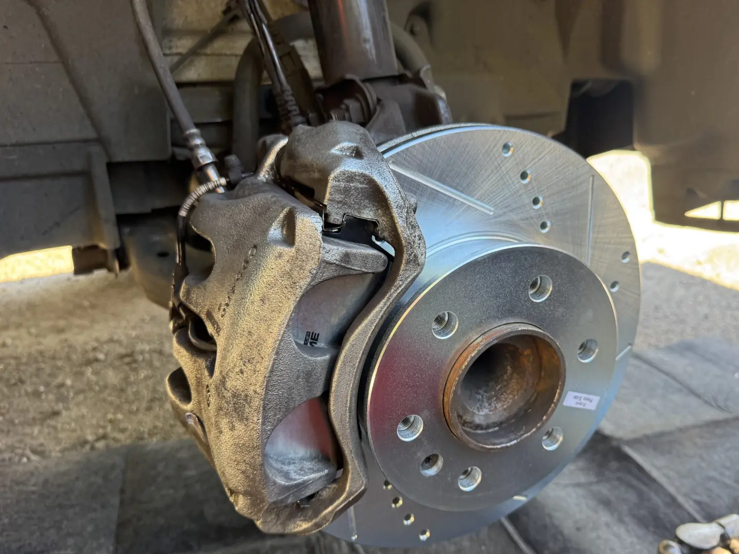 Slotted and drilled front brake rotor installed on a 2023 Mercedes-Benz Sprinter.