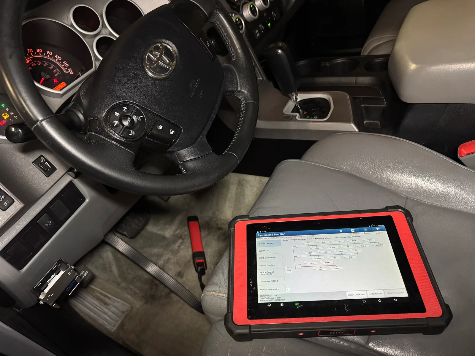 Diagnostic scan tool connected inside a Toyota while dashboard warning lights are illuminated.