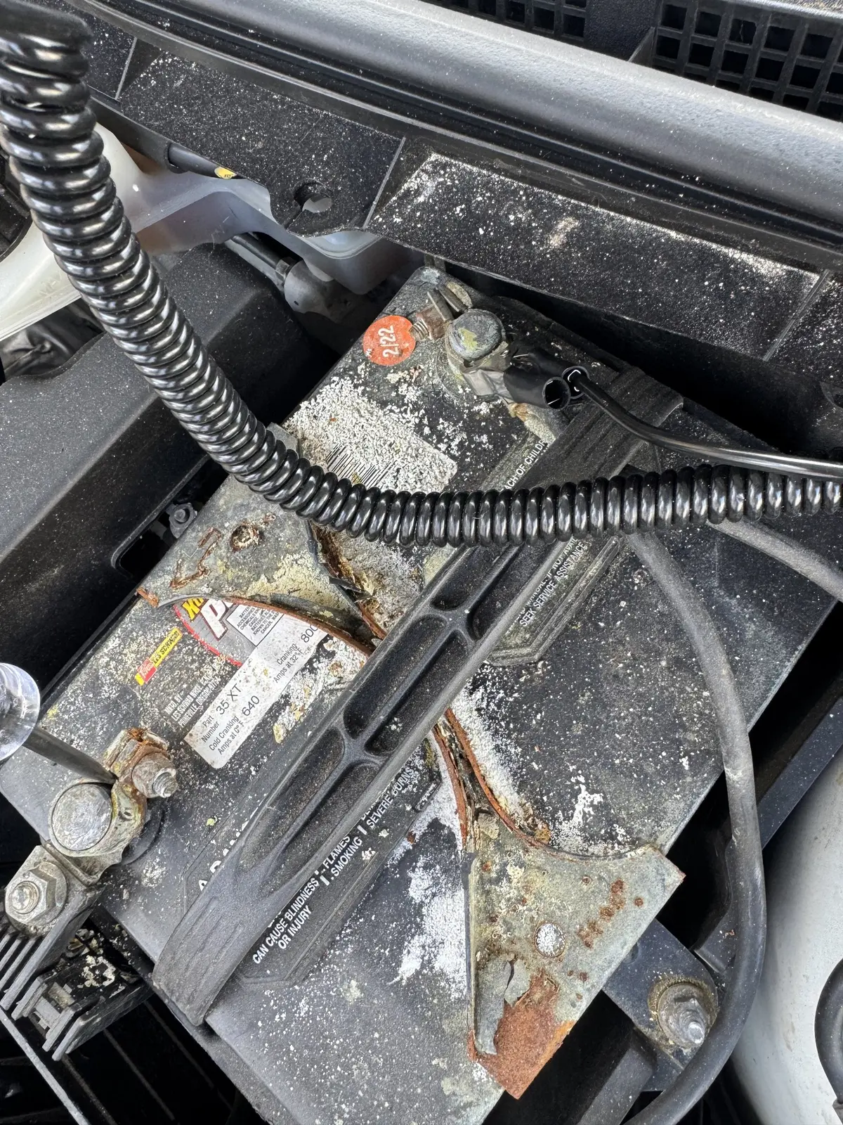 Old battery and terminals before replacement in a 2013 Mazda3.