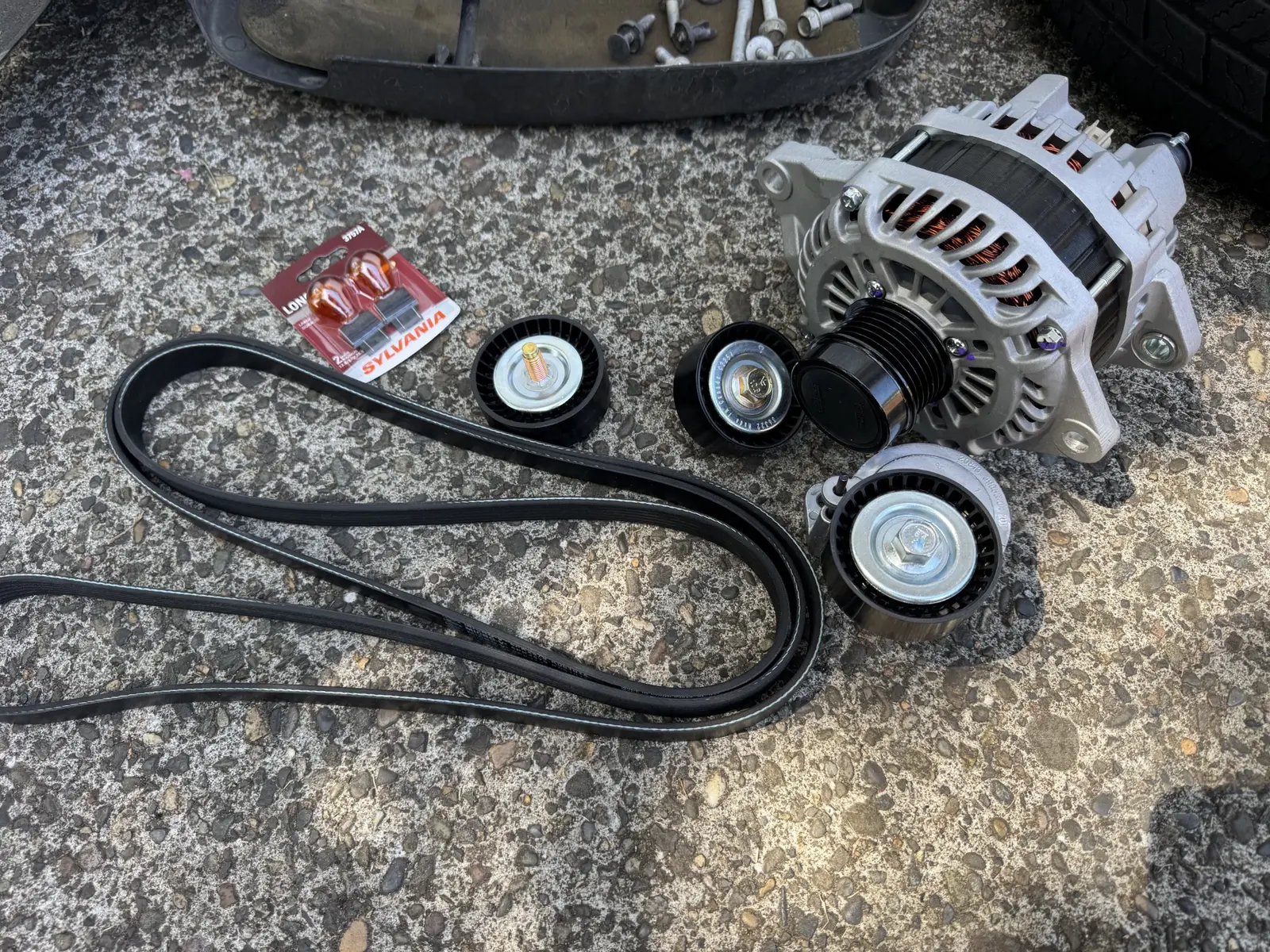 New alternator, belt and drive pulleys prepared for installation on a 2014 Jeep Patriot.