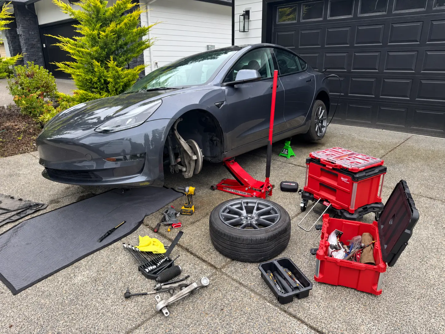 Tesla Model 3 with its front wheel removed during mobile suspension repair.