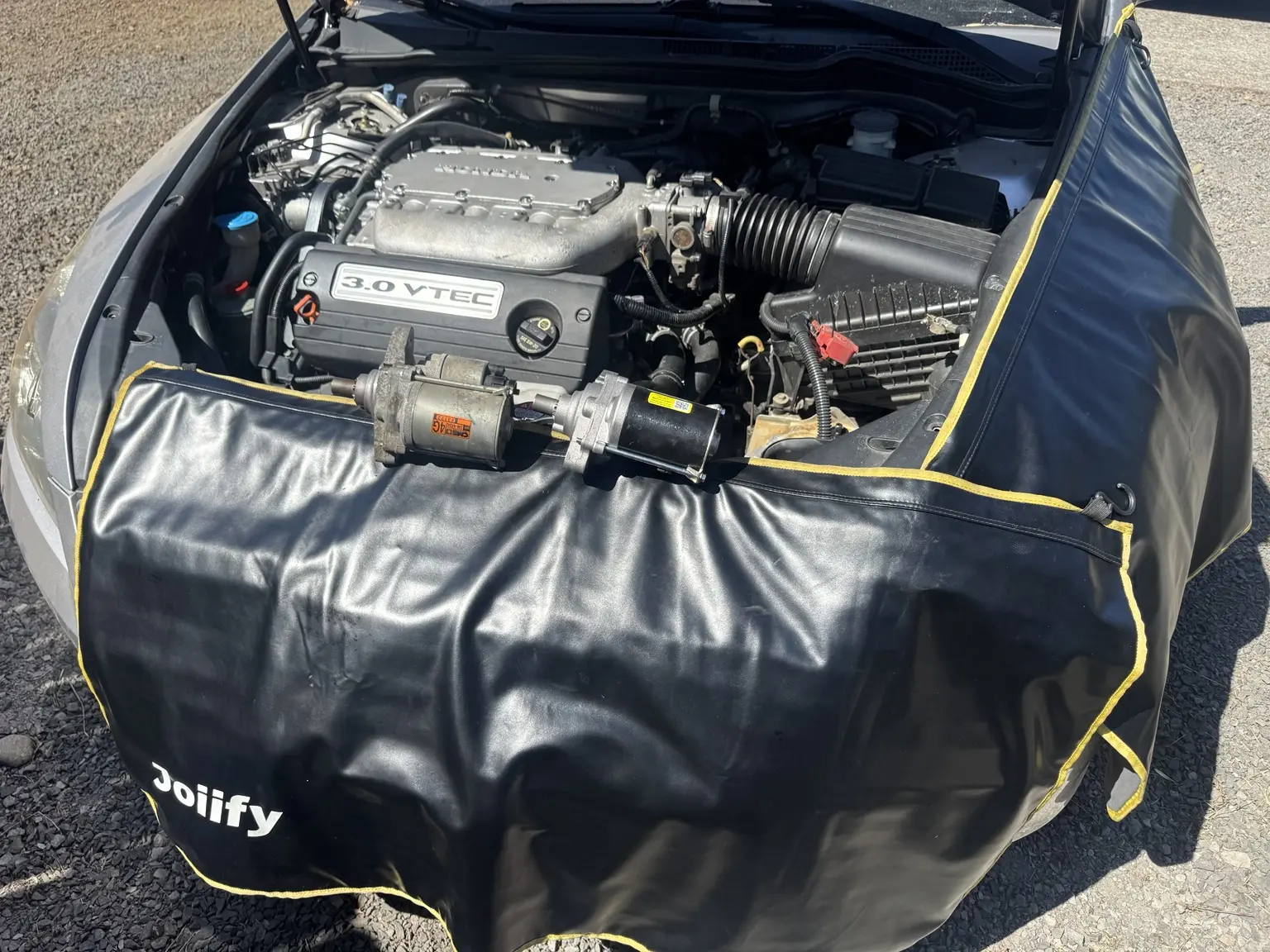 Two starter motors positioned on a fender cover above the open Honda Accord engine bay.
