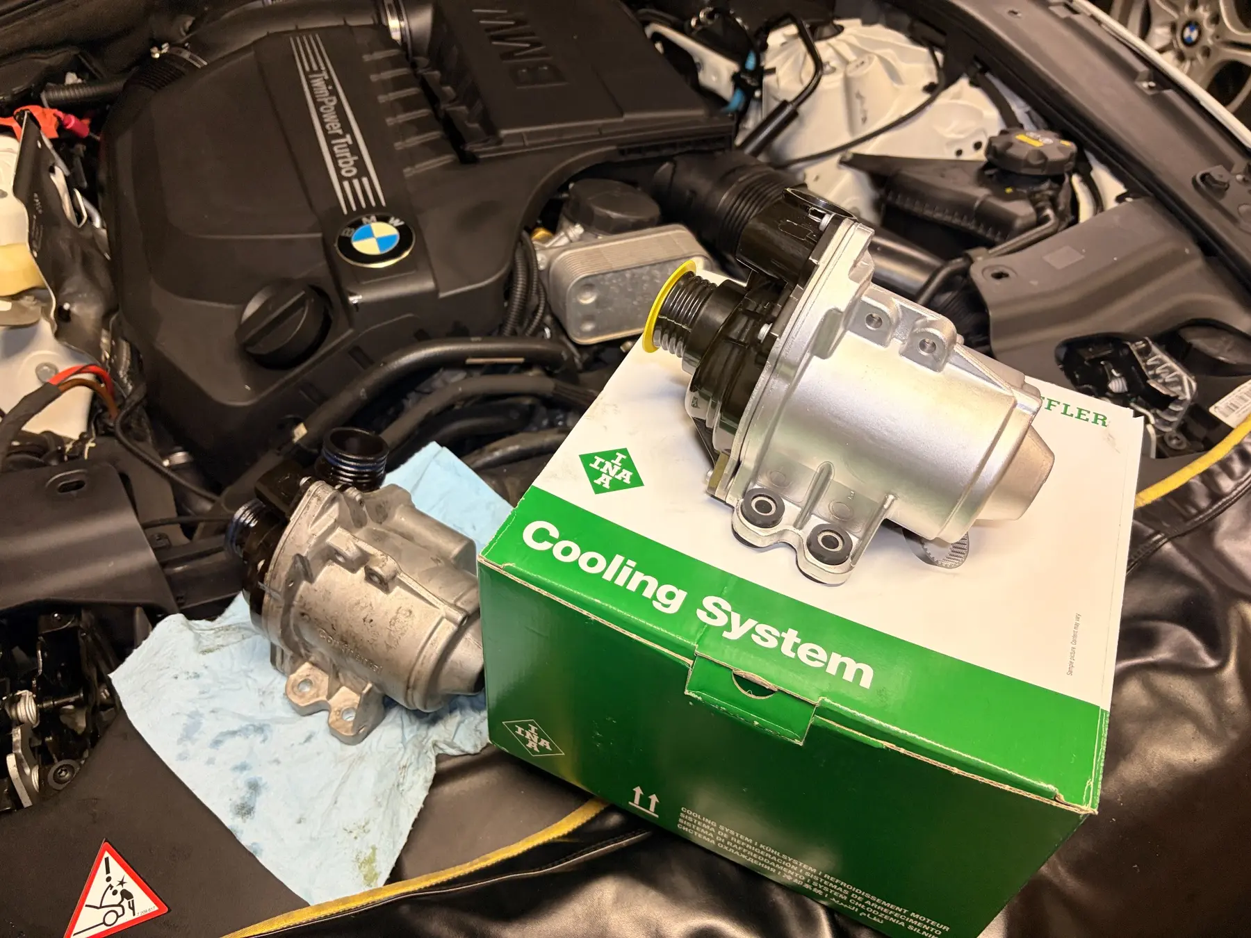 Old and replacement water pumps above the BMW 640i engine bay
