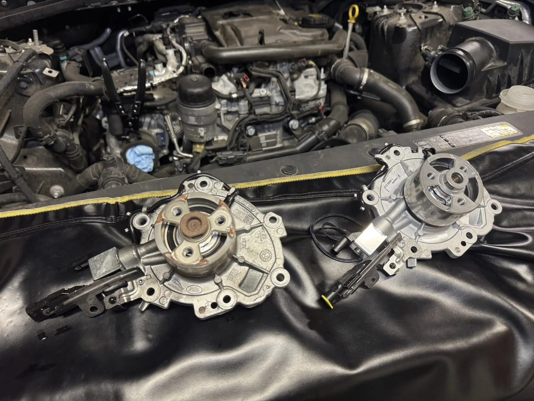 Removed and replacement water pumps in the Land Rover Defender engine bay