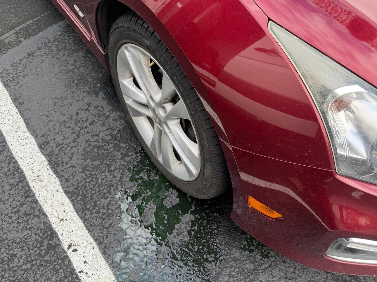 Coolant puddle beneath the front of a red vehicle